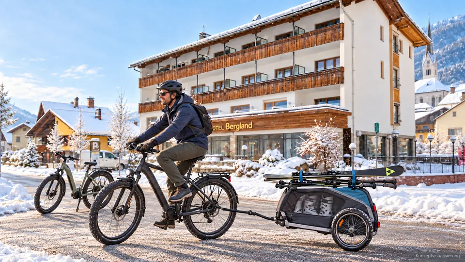 Konzeptbild: Ein Gast fährt in normalen Winterschuhen vor dem Hotel Bergland mit einem Fahrrad und einem Anhänger für Ski und Skischuhe los.