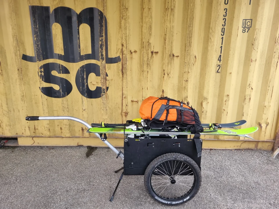 Ski und Rucksack auf dem Wagen mit den schwarzen Bordwänden.