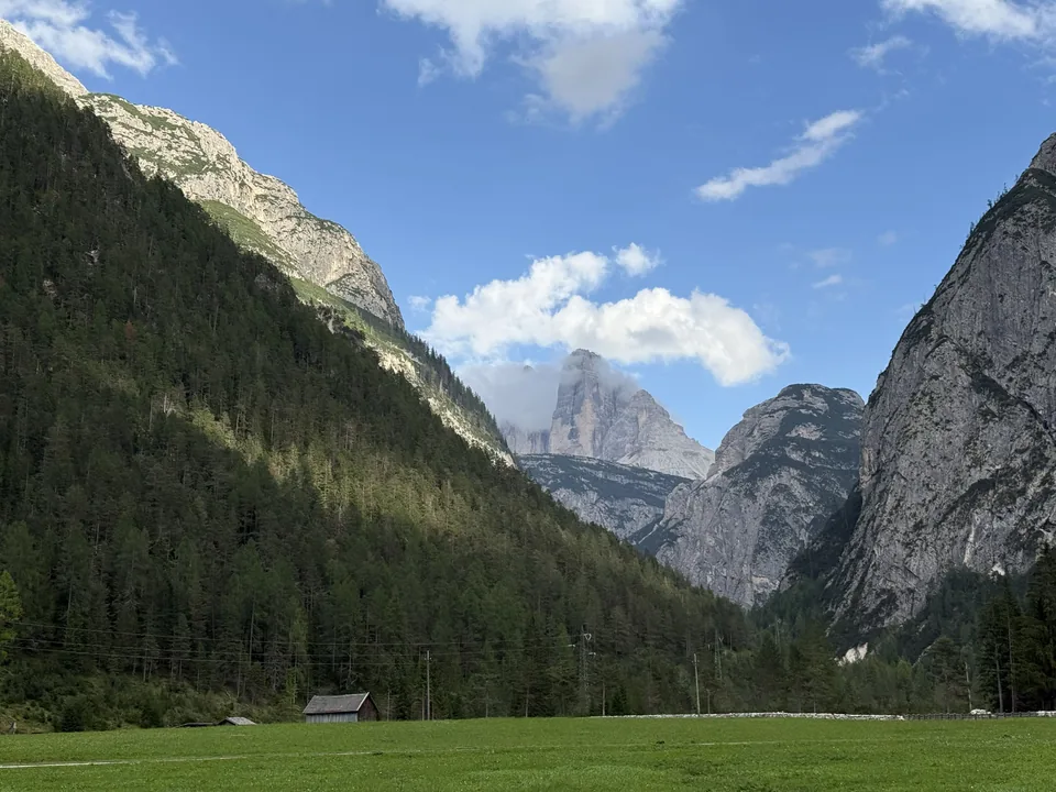 Blick durch ein bewaldetes Tal auf die Felstürme der Drei Zinnen