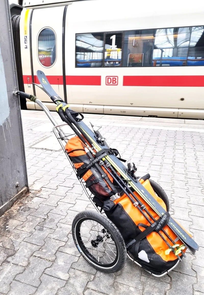 Beladener Trolley vor einem Zug.