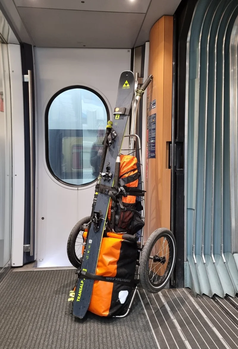 Beladener Trolley aufrecht im Eingangsbereich eines Zuges.