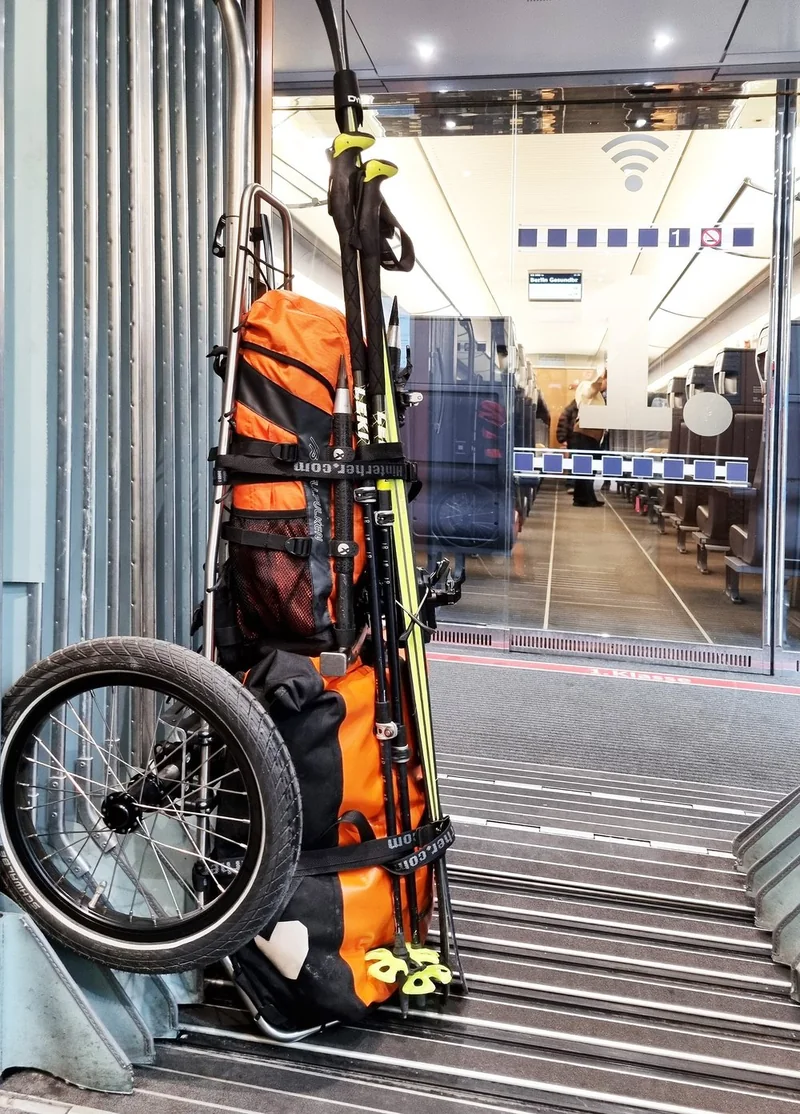 Trolley mit seitlich verstauten Rädern im Zug.